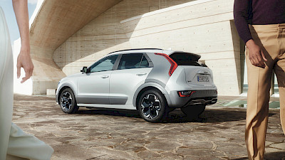 Egy férfi és egy nő elsétálnak a Kia Niro mellett