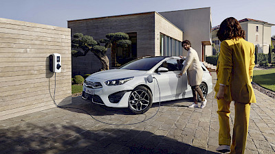 A Kia Ceed mellett álló férfi egy nőre tekint