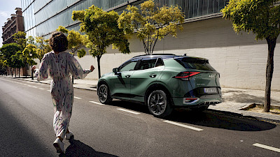 Nő sétál a Kia Sportage felé az utcán