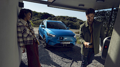 Egy férfi és egy nő beszélgetnek az MG ZS EV töltése közben