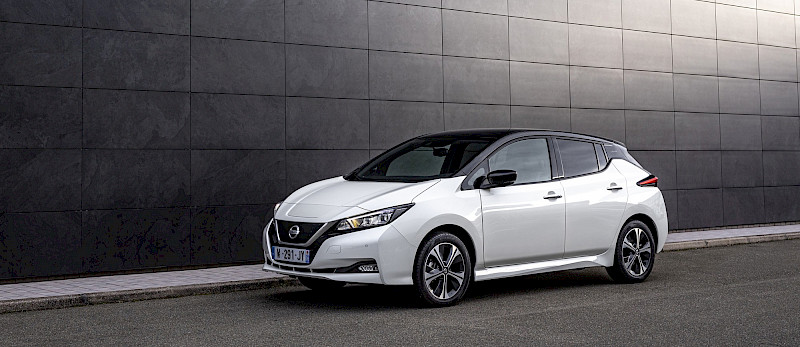 Nissan Leaf modell parkol a fekete burkolatú fal előtt