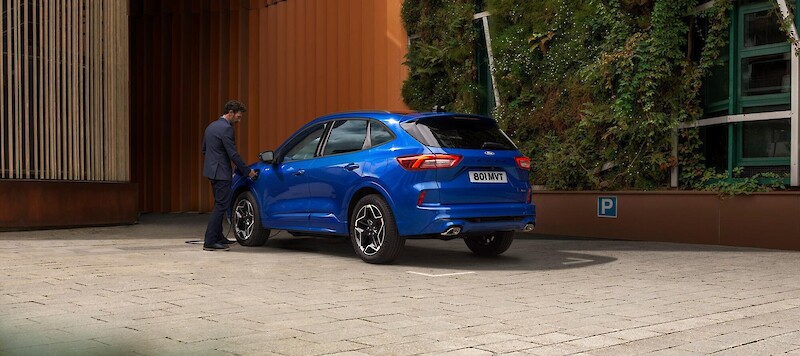 Férfi töltőre helyezi a Ford Kuga PHEV modellet