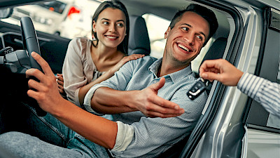 Egy férfi és egy nő átveszik a kulcsot egy személyautóban ülve