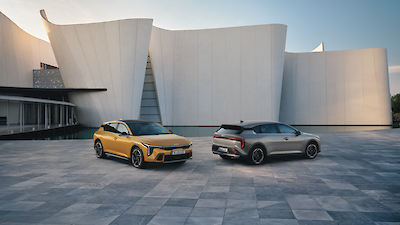 Kia K4 modellek állnak a modern épület előtti térkövön